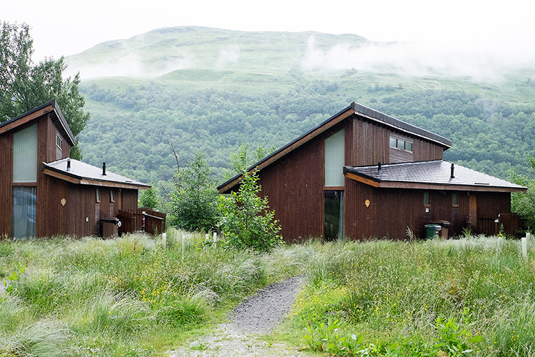 Photo shows log cabins in the West Coast of Scotland on a misty, overcast day.