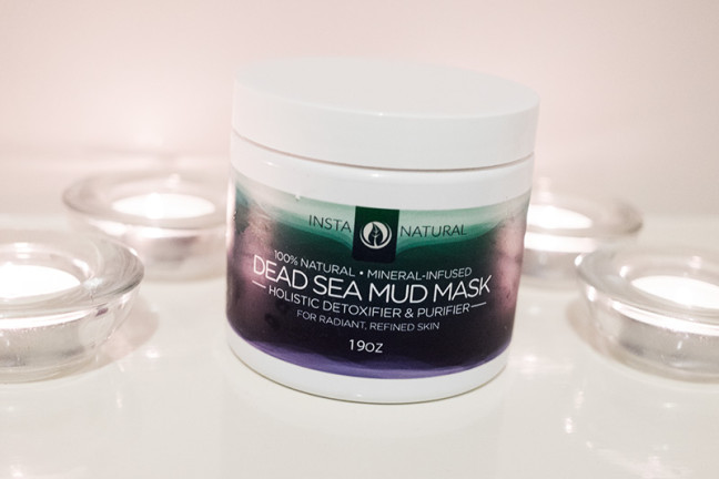 Photo shows the InstaNatural Dead Sea Mud Mask sitting on a white shelf surrounded by tealight candles.