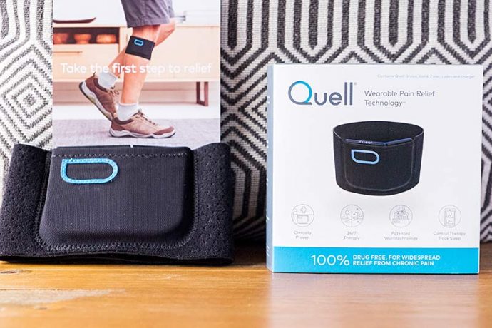 A photograph of the Quell pain relief device. Showing the Quell sports band, Quell wearable pain relief box that reads 100% drug free relief from chronic pain.