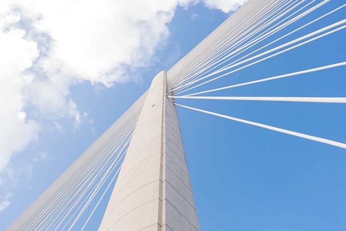 Photograph shows a close-up of one of the supports with the cables spanning from either side.