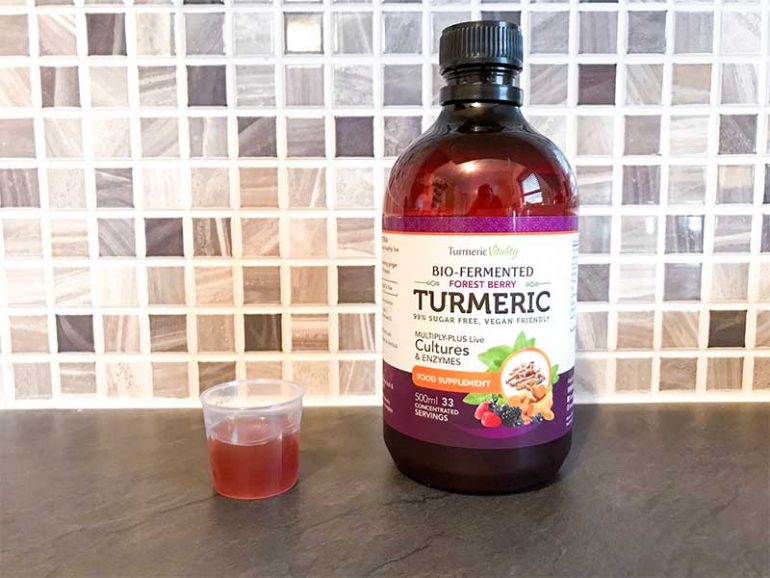 Photo shows a bottle of berry flavoured liquid turmeric with a 15ml dose measured out.