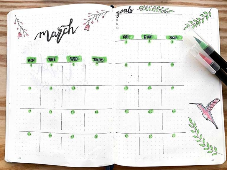 March bullet journal monthly spread is titled with the month and has a calendar layout. There is an area for writing goals at the top right. Flower buds, leaves and a hummingbird decorate the page.
