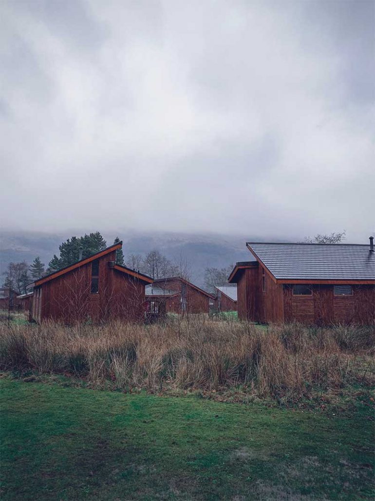 Photo of the Forest Holidays Argyll wooden cabins taken on a misty, wet day.