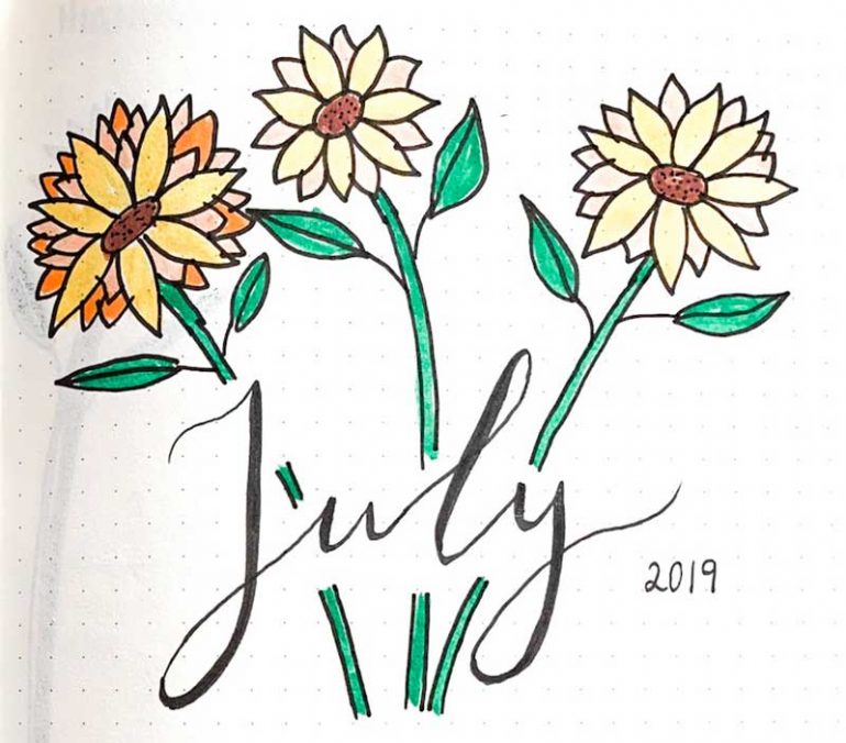 Title image in my July bullet journal set up. July is handlettered with 2019 written beside it. Three yellow flowers are drawn around the word.