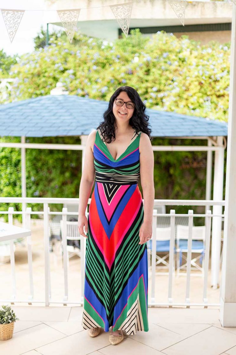 Donna smiles at the camera wearing a bright, colourful maxi dress
