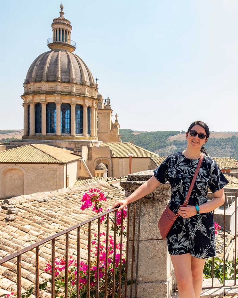 Photo shows Donna stood resting against a railing in Ragusa, Sicily. Rooftops and the dome of the Duomo di San Giorgio can be seen in the background.