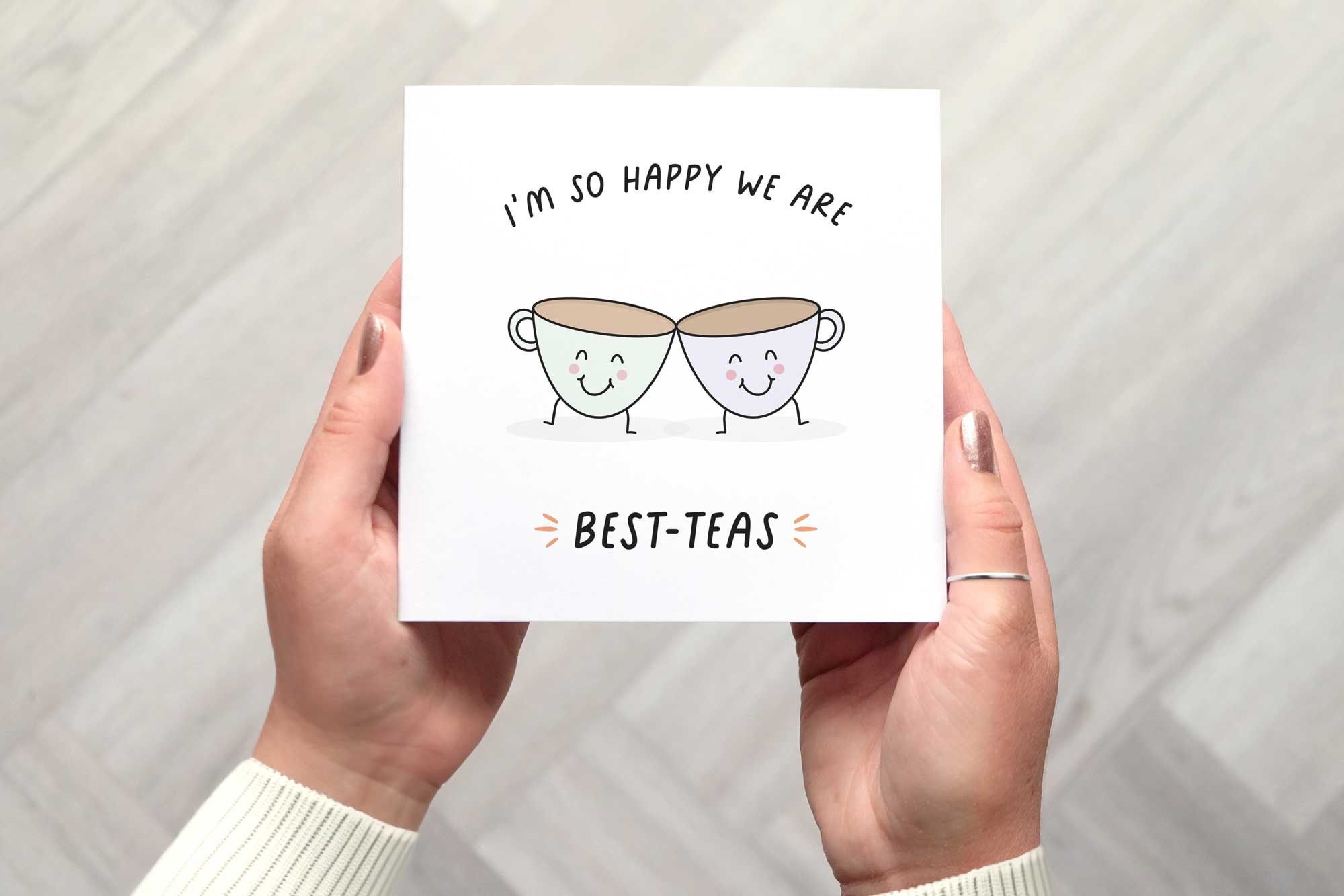 This friendship card features two cute illustrated smiling cups of tea leaning towards each other. One is lilac and the other pastel mint green. The card reads Im so happy we are best teas.