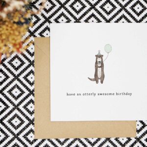 A fun birthday card featuring a cute otter that is wearing a green party hat with grey pom pom that is holding a green balloon. Card reads have an otterly awesome birthday.