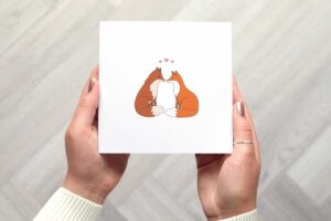 This cute valentines day card features two illustrated foxes sitting looking at each other with three small pink love hearts above their heads.