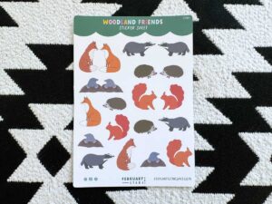 Woodland friends sticker sheet against a black and white geographic background. The sticker sheet has small individual stickers of foxes, badgers, hedgehogs and moles.