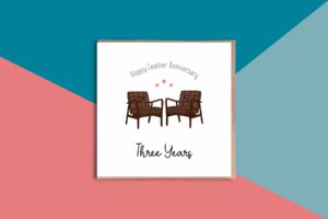 A super cute third wedding anniversary card that reads Happy Leather Anniversary Three Years. Between these words are two illustrated midcentury modern leather chairs with smiling faces. There are three love hearts above them. The card has a white background.