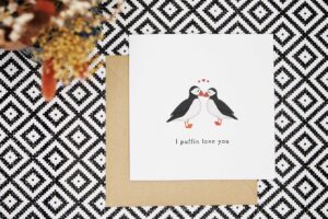 This love card has a minimalist design with an illustration of two puffins stood facing each other with beaks together. Underneath it reads I puffin love you