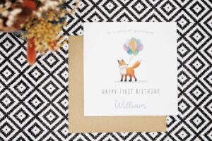 This very cute personalised birthday card features an illustrated fox holding a bunch of multi coloured helium balloons in its mouth. The card can be personalised to feature the Childs relation to you, age and name. This example reads to a special grandson. Happy First Birthday William and the number 1 in front of the balloons.
